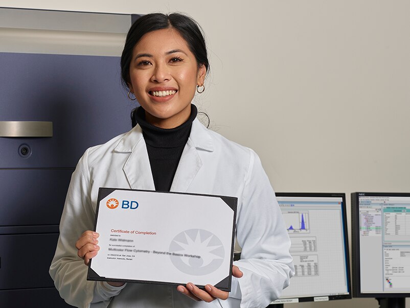 Scientist holding a certificate of completion for a Multicolor Flow Cytometry Beyond the Basics Workshop. 